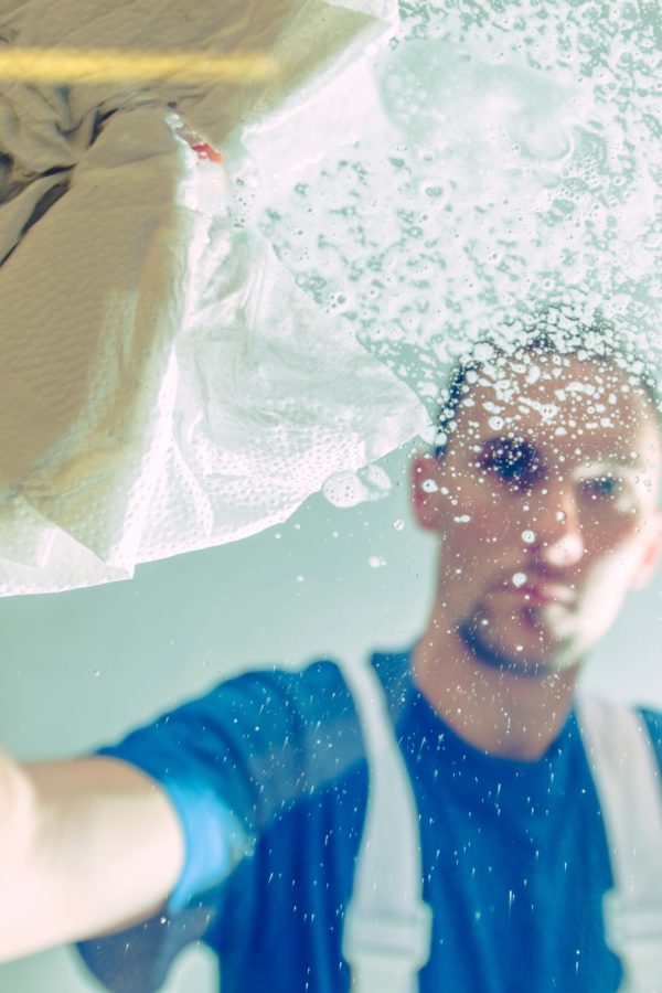 Men Cleaning Office Windows. Windows Detergent Spraying and Cleaning by Caucasian Male. Cleaning Service Worker.